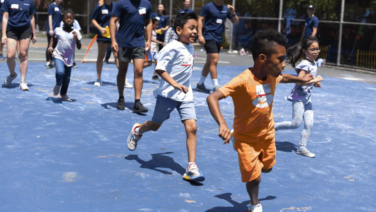 Two young boys smiling and running with other children