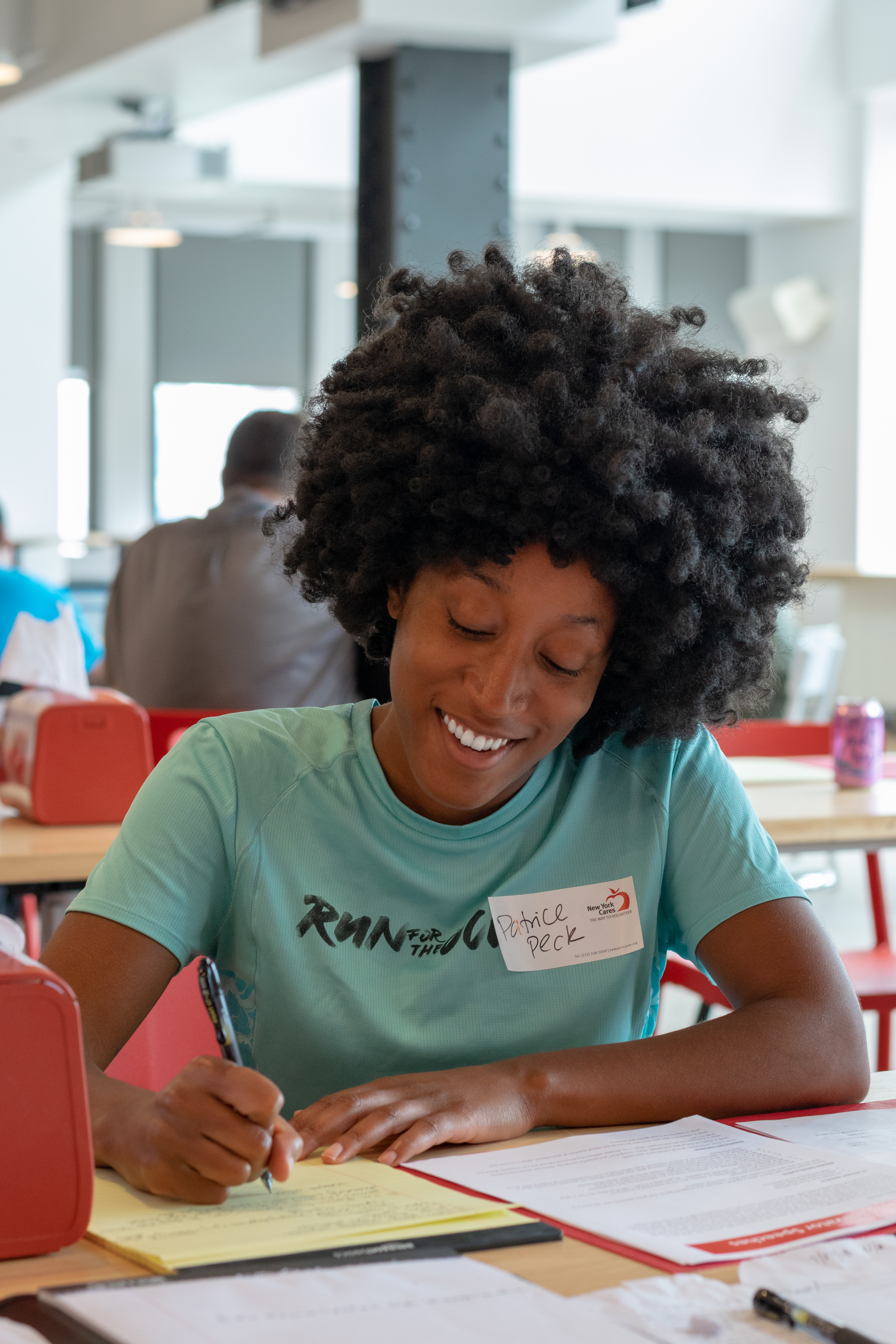 A young woman smiles as she writes something on a yellow legal pad during a job readiness fair