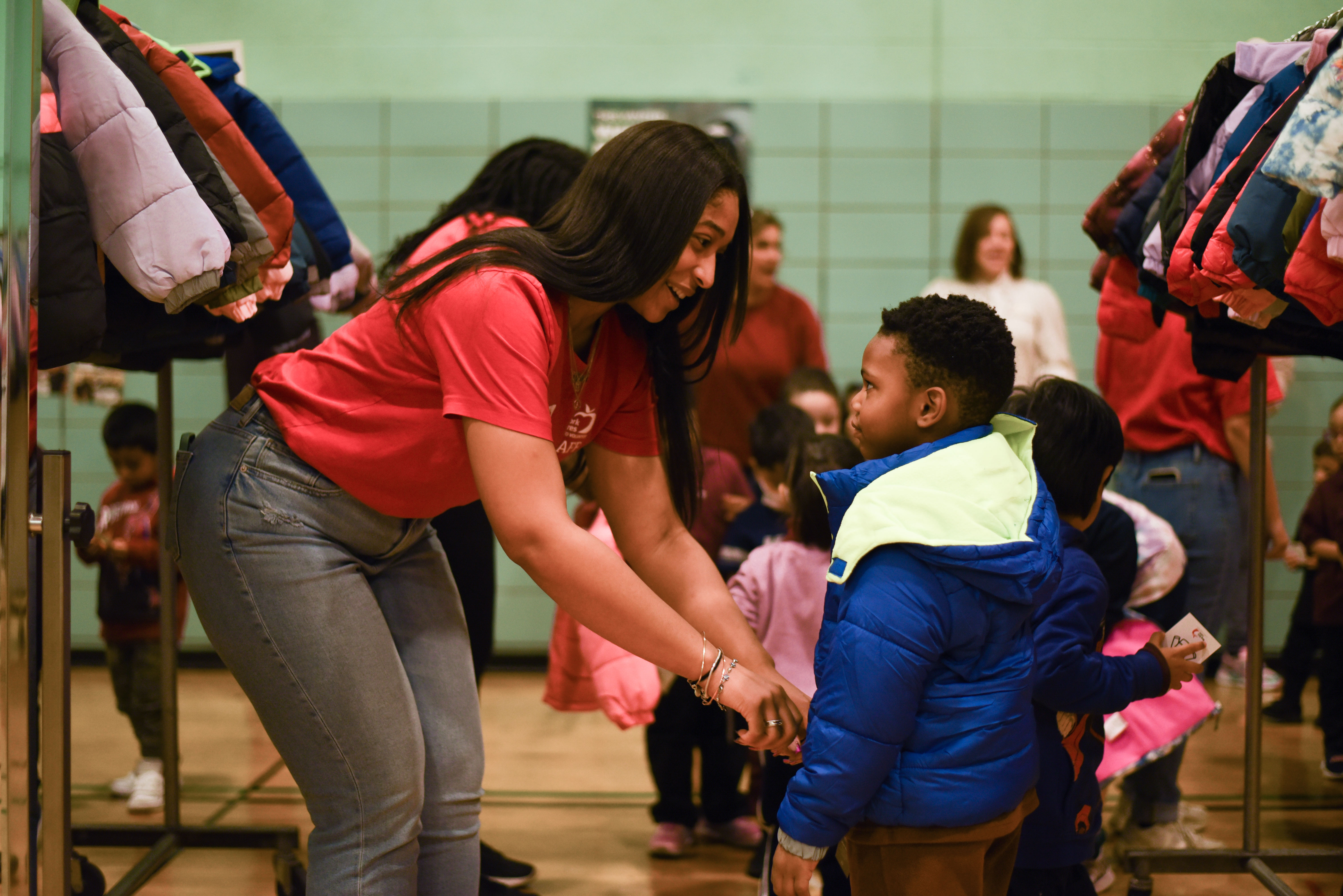 New York Cares staff member helping student try on a new coat