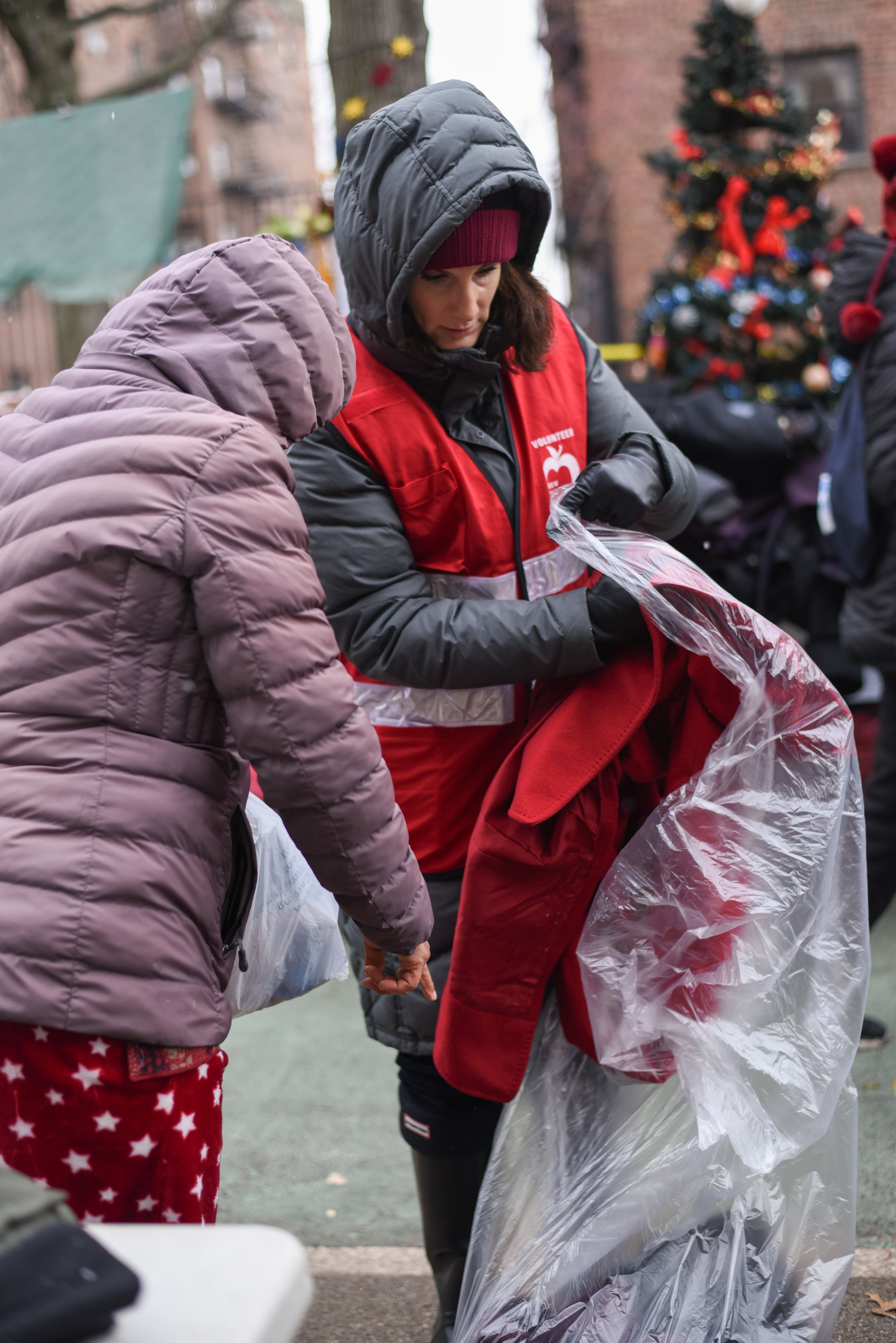Staff member helping a Queens resident pick out a coat outdoors