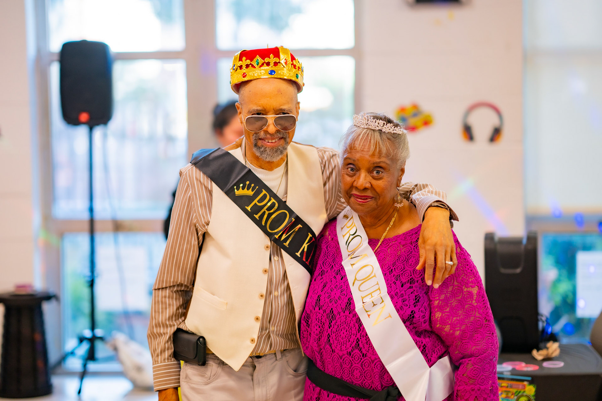 Two older adults posing in prom sashes