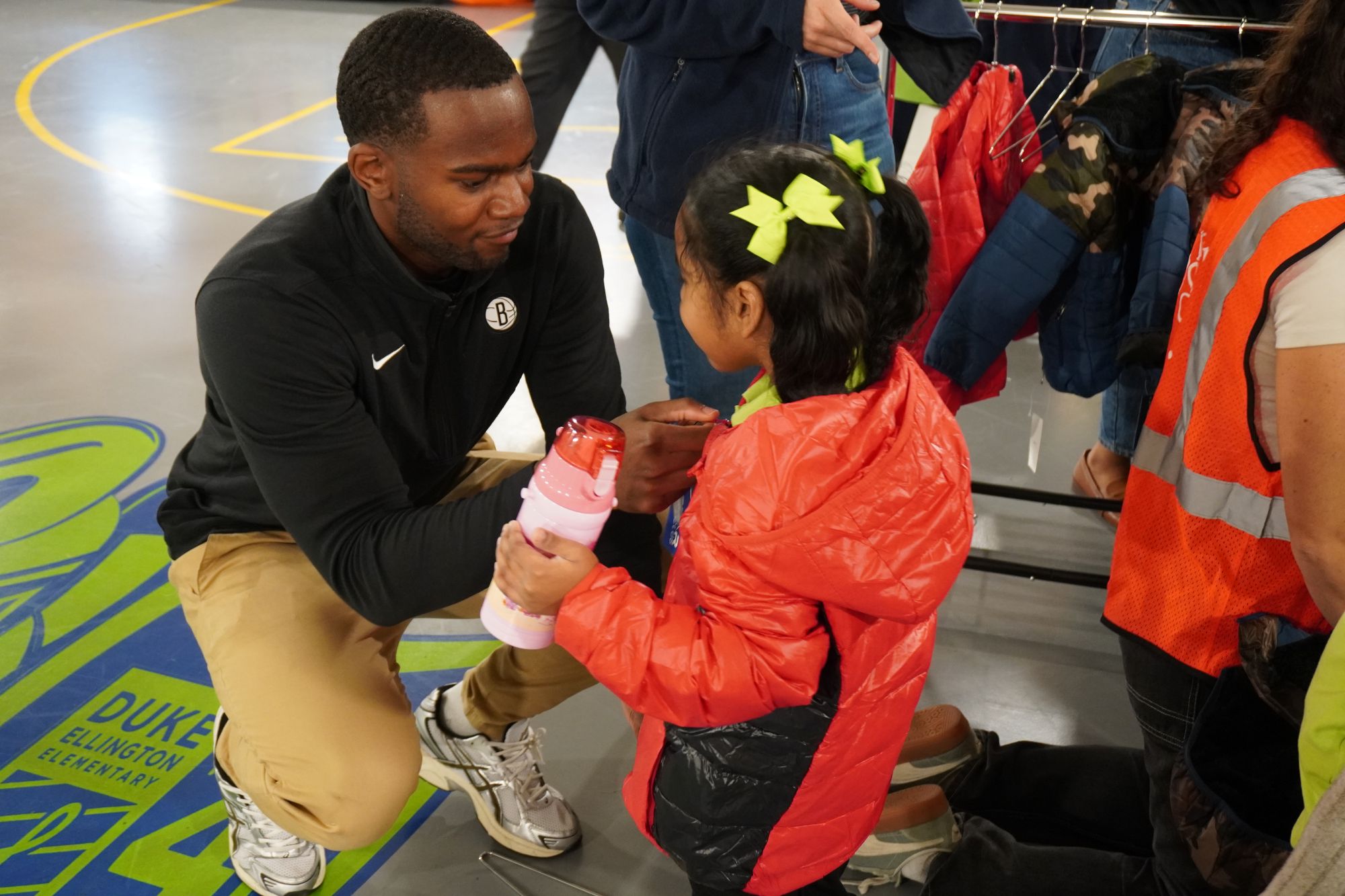 Volunteering helping a student try on a coat
